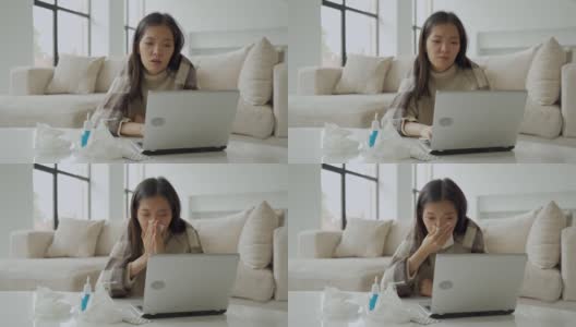一个亚洲女人用餐巾擤鼻涕，坐在家里的办公桌旁，用笔记本电脑学习，一个生病的女人得了流感，用毯子盖住自己，得了感冒高清在线视频素材下载