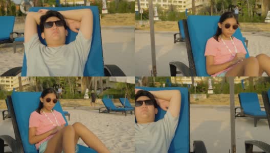 快乐的亚洲孩子戴着太阳镜在海滩椅上放松在早上在酒店或度假村度假，与家人，生活理念。高清在线视频素材下载