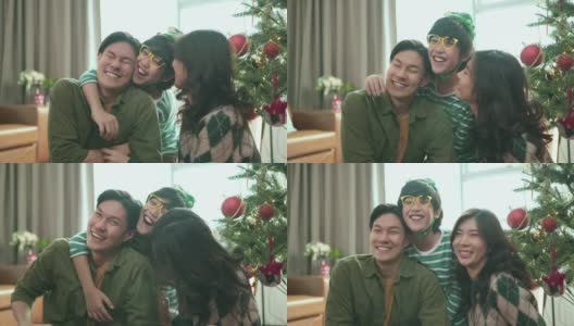 亚洲甜蜜的家庭坐在客厅微笑的肖像。儿子用爱的手拥抱着父母，从背后牵着父亲和母亲的胳膊，幸福快乐地庆祝圣诞夜的节日高清在线视频素材下载