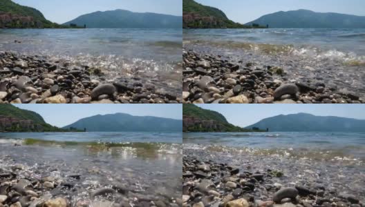 景观拍摄卵石，迎面而来的海浪和山脉。高清在线视频素材下载