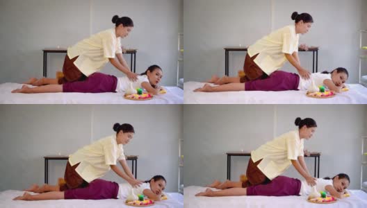 泰国按摩师正在泰国水疗中心用慢动作给一位女士进行背部按摩。高清在线视频素材下载
