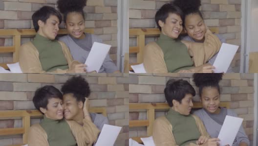 非洲裔美国女孩展示她的家庭作业或贺卡给年轻的亚洲妇女惊喜后完成了母亲节的研究高清在线视频素材下载
