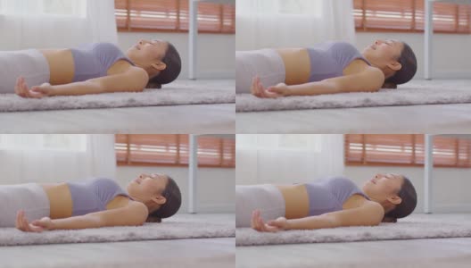 平静的亚洲女性练习瑜伽的尸体或Savasana姿势冥想微笑在家里舒适和放松，健康的女性做瑜伽nidra放松她的身体，瑜伽保健概念高清在线视频素材下载