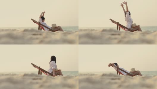 年轻的亚洲女性伸展双臂举起感觉放松躺在沙滩上的躺椅上。夏天度假的概念。高清在线视频素材下载