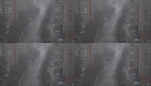 从窗口观看，近距离的雪花与城市的背景高清在线视频素材下载