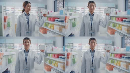 药店:亚洲职业女性药剂师的肖像拿着模拟模板药品包装跟踪标记，看着相机，微笑。专家推荐最佳产品高清在线视频素材下载