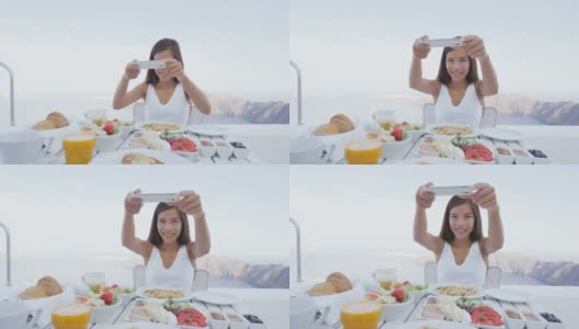 女人用手机app拍早餐照片。女孩在奢华旅行度假时拍美食照片，用于社交媒体。欧洲希腊圣托里尼度假胜地的美女。高清在线视频素材下载