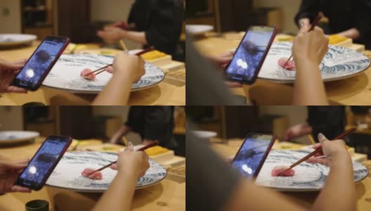 在一家日本小餐馆里，一位女士正在用智能手机拍寿司高清在线视频素材下载