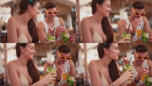 年轻的男人和女人在热带海滩酒吧喝鸡尾酒高清在线视频素材下载