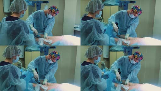 手术室:抽脂手术准备。一组外科医生给一个女孩做抽脂手术。外科医生的工作就像插管。高清在线视频素材下载