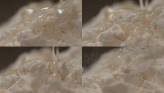慢镜头，宏观镜头:透明液体从面包房的一堆面粉上流下。高清在线视频素材下载