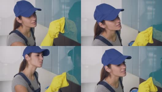 年轻漂亮的清洁女工穿着制服，戴着黄色手套擦拭厨房家具高清在线视频素材下载