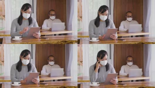 两个亚洲商务人士同事戴着防护口罩在家里办公，商业伙伴一起工作的新项目高清在线视频素材下载