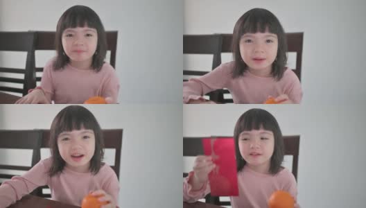 亚洲的中国女孩看着笔记本电脑的摄像头，拿着红包和橘子向她的祖父母祝贺春节高清在线视频素材下载