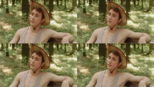 一个戴着草帽的年轻人在树林里感到很惊讶。高清在线视频素材下载