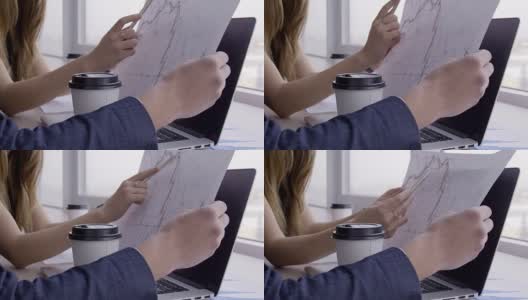 在服务台的女人手里拿着一支笔给男人看一张纸上的图表高清在线视频素材下载