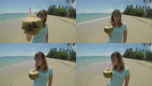 肖像:快乐的游客举起她的椰子，喝了一口可口的果汁。高清在线视频素材下载