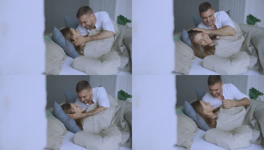 年轻貌美的情侣在清晨醒来。帅哥在床上亲吻和拥抱他的妻子高清在线视频素材下载