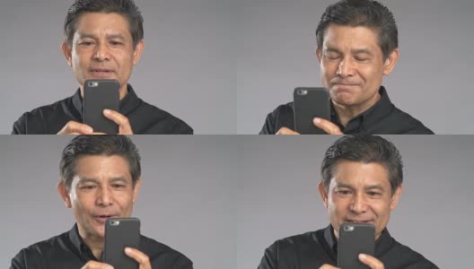 特写的高级男子拍摄视频与他的手机孤立在灰色背景。穿着黑衬衫的亚洲人。高清在线视频素材下载