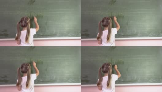 一个小女孩在黑板上用粉笔写字母。幼儿园education.4k高清在线视频素材下载