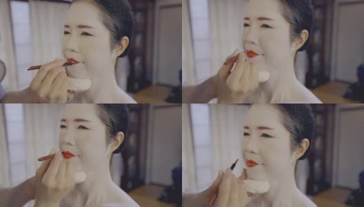 一名日本女性为艺妓化妆，涂上红唇高清在线视频素材下载