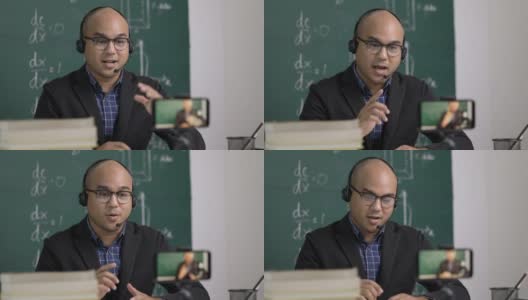 印度年轻教师男子戴着耳机坐着通过智能手机进行在线视频会议直播。亚洲数学教师在线授课，供学生在线学习。高清在线视频素材下载