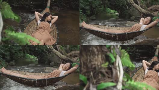亚洲女人放松睡在吊床上的自然森林与小溪高清在线视频素材下载