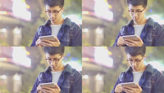 亚洲男子学生晚上在街上拿着手机高清在线视频素材下载
