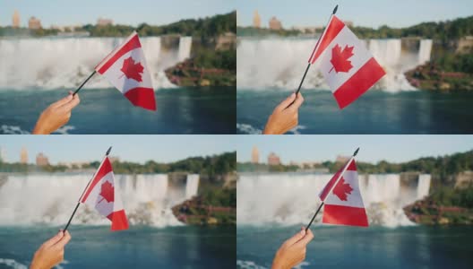在尼亚加拉大瀑布的背景下，一只女性手举着加拿大国旗。在加拿大旅游高清在线视频素材下载
