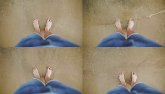 人的脚被海浪洗干净，埋在沙子里。一个穿着蓝色牛仔裤的白人男子把脚上的水刷掉，进入了大海。大海或海岸上的男性腿部特写。高清在线视频素材下载