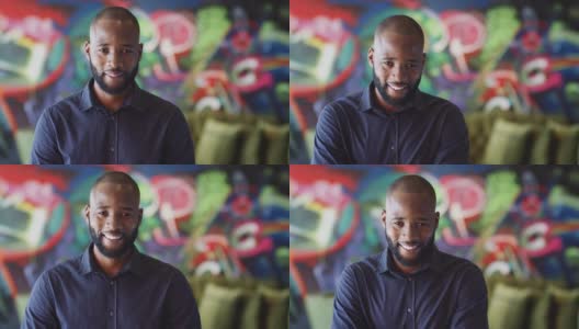 千禧黑人男性创意在工作场所的壁画前对着镜头微笑，头和肩膀高清在线视频素材下载