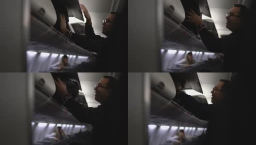 在飞机上把行李放在行李架上的人高清在线视频素材下载