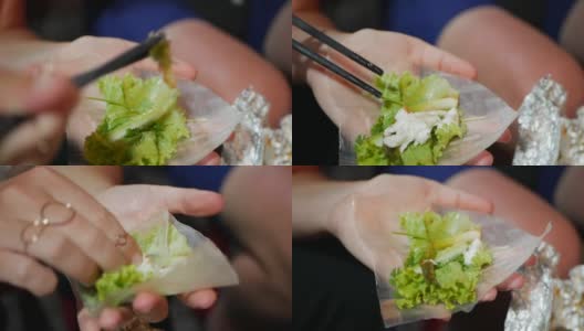 游客准备和吃春卷的米纸包装或banh trang在晚上的街头小吃市场。传统越南nem菜，亚洲美食。近距离高清在线视频素材下载