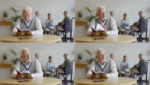 架上集中了三位老人，两位老年妇女和坐轮椅的残疾老人，在养老院打牌。戴眼镜的聪明老人在餐桌上看书思考高清在线视频素材下载
