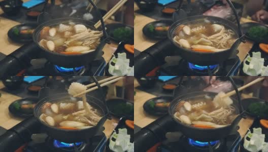 这名男子用筷子将鱿鱼从涮锅中取出。一家人在日本餐馆吃涮锅晚餐。和家人一起吃涮锅饭。高清在线视频素材下载
