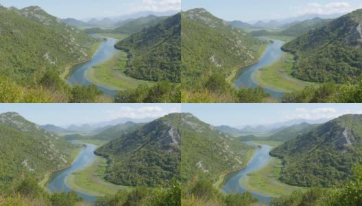蓝色的河流穿过绿色的山谷，流向远方的群山。在黑山国家公园蜿蜒曲折的克诺耶维察河，蜿蜒穿过山间的沼泽，通往斯卡达湖高清在线视频素材下载