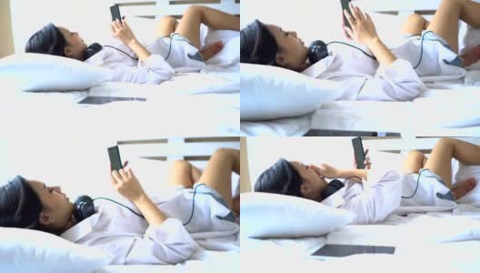 特写:美丽的女人躺在床上，打着哈欠与智能手机高清在线视频素材下载