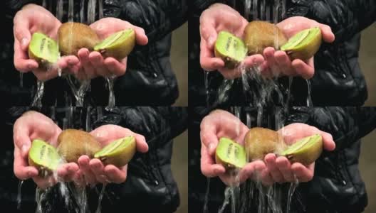 水在人手中新鲜的切片猕猴桃上流动高清在线视频素材下载