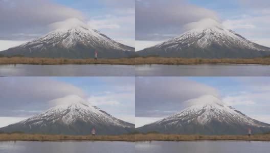 慢镜头——旅行者漫步到新西兰北岛的塔拉纳基火山的景色中，在湖中看到山和攀登者的倒影。新西兰被高清在线视频素材下载