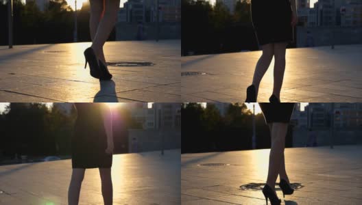 跟随女性的腿高跟鞋走在城市街道在日落时间。年轻的女商人穿着高跟鞋进城。女孩走的户外。慢动作特写侧视图高清在线视频素材下载