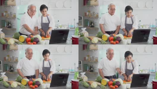 一对亚洲老年夫妇在家做饭时使用笔记本电脑。70年代老年男女关系退休生活方式概念高清在线视频素材下载