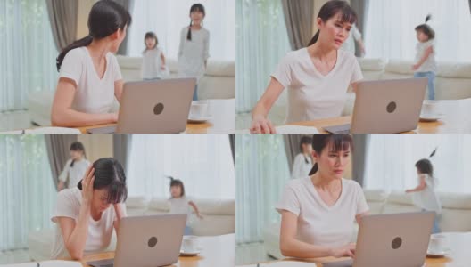 亚洲女商人因COVID-19封锁在家工作，孩子们在玩耍。自由职业母亲失去了她的注意力在工作在电脑，感到沮丧的年轻女孩制造噪音。高清在线视频素材下载