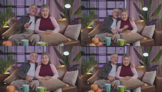 老退休的老亚洲夫妇在家里看电视，老成熟的亚洲夫妇一起在客厅的沙发沙发上欢笑胜利的体育比赛助威活动高清在线视频素材下载