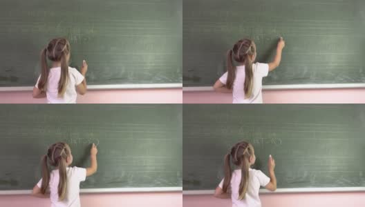 一个小女孩在黑板上用粉笔写字母。幼儿园education.4k高清在线视频素材下载