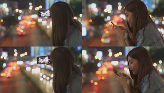 年轻美丽的亚洲女孩在夜晚走在城市里，喜欢用手机应用程序的智能手机相机拍下照片或记录下夜晚灯光照亮的城市景观的视频。高清在线视频素材下载