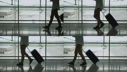 男性年轻乘客带着行李在机场候机楼出发区行走。穿着休闲装出差的亚洲商人。现代旅游生活理念。高清在线视频素材下载