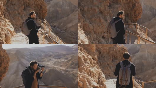 古山路上的白人男性游客。手持智能手机和相机的男子欣赏以色列沙漠遗址。4 k高清在线视频素材下载