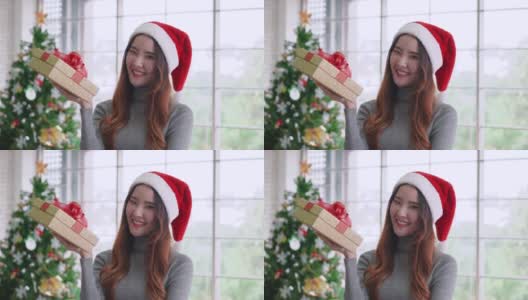 年轻的亚洲女孩拿着圣诞礼物，与微笑的脸高清在线视频素材下载