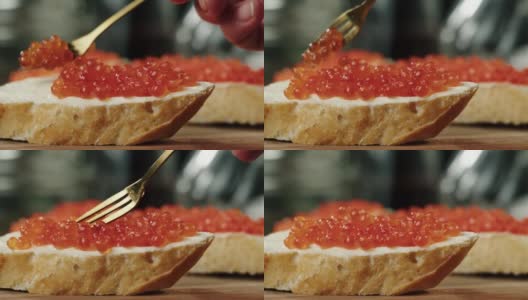 把红鱼子酱放在面包和黄油上，鱼子酱三明治的特写镜头。三文鱼腌橙籽。生海鲜。豪华美食。鱼制品美味可口。俄罗斯菜高清在线视频素材下载