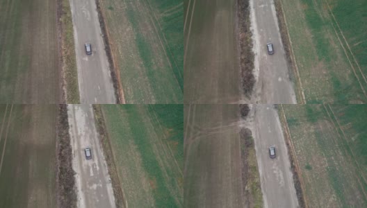 这辆车正行驶在穿过田野的道路上，无人机拍摄了航拍画面。秋天的时候在柏油路上，摄影机跟在车的后面。高清在线视频素材下载